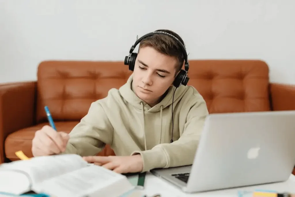 Focused learner wearing headphones studying English with laptop